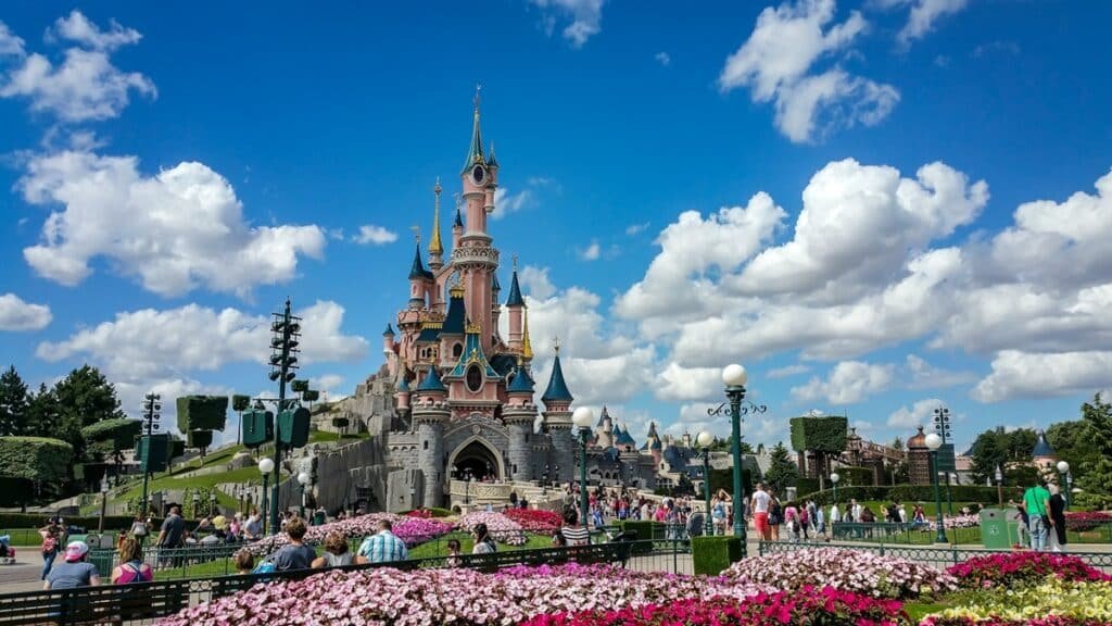 Disneyland castle surrounded by flowers and a crowd of people