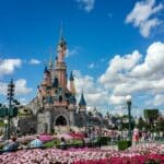 Disneyland castle surrounded by flowers and a crowd of people