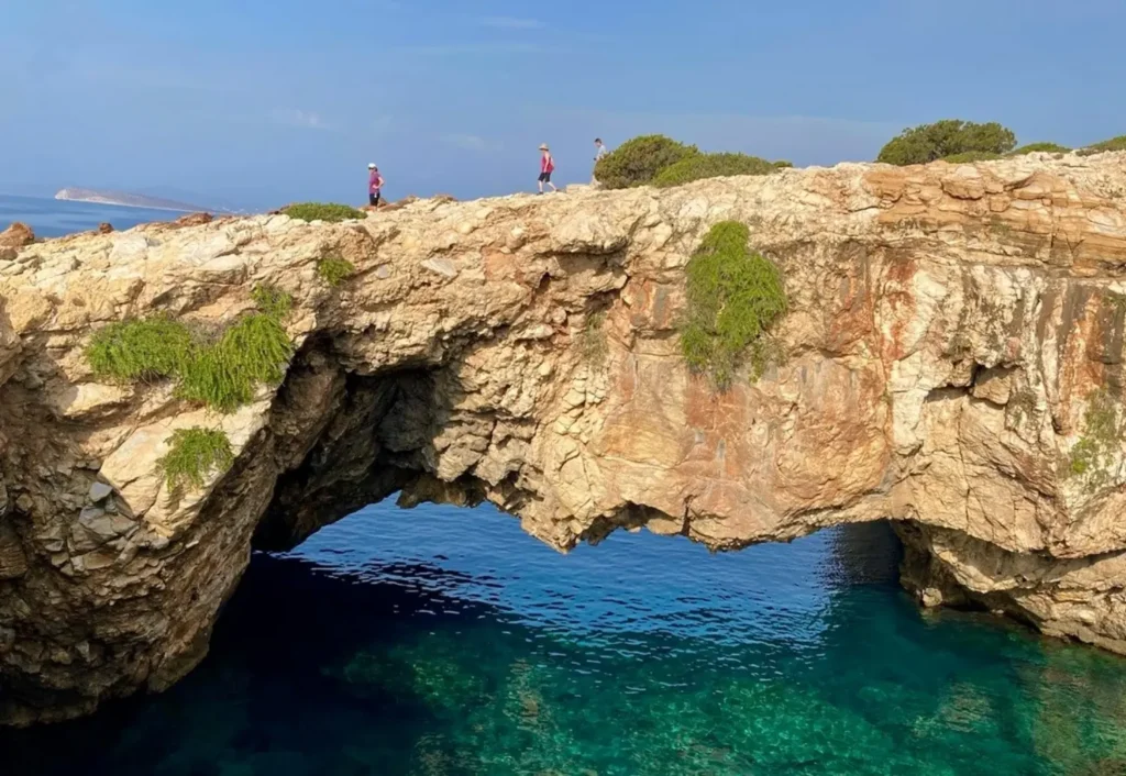 A family hiking across a natural rock bridge in Paros during a multi-generational vacation