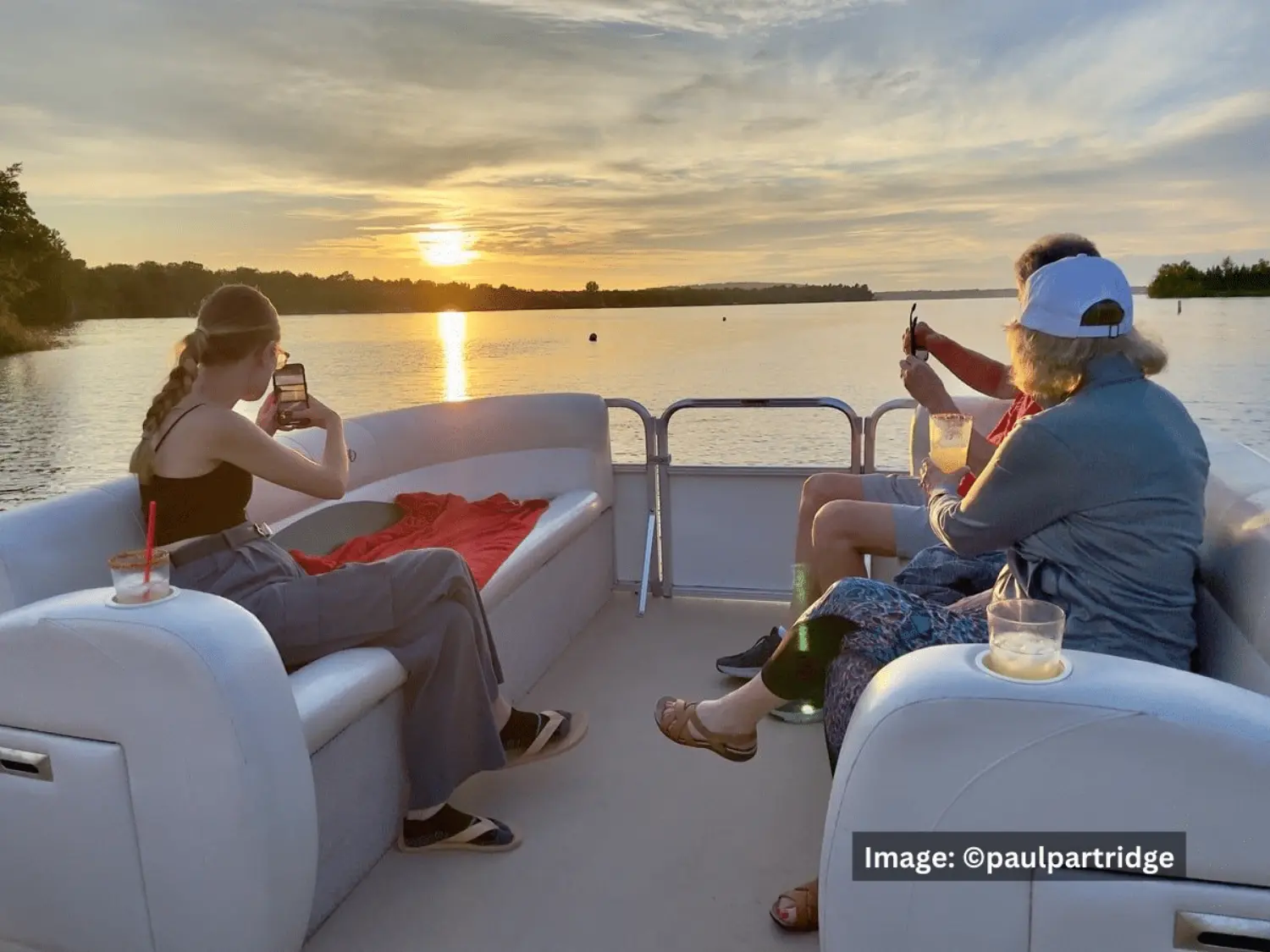 A family enjoying a sunset boat ride and taking photos during a multi-generational vacation