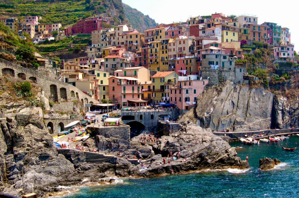 Cinque Terre's cliffside village with colorful houses, boats, and people by the water