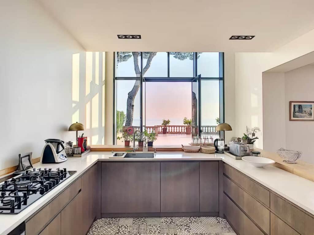 Modern kitchen with sleek cabinetry, patterned tile floors, and large windows offering stunning sea views