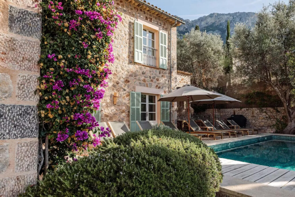 Charming stone villa with lush bougainvillea, poolside loungers and umbrellas