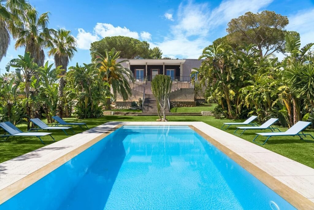 View of the pool and lush tropical garden at Sicilian Song, a family-friendly villa in Sicily.