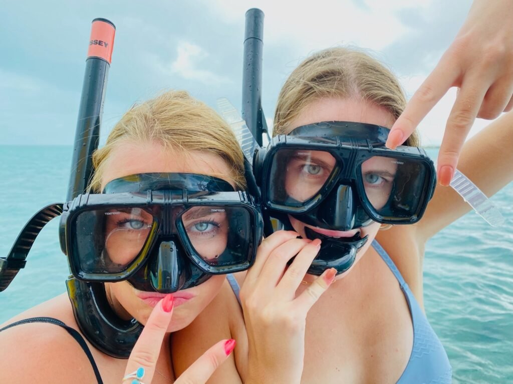 Two women wearing snorkel masks posing playfully in the ocean during a friends' reunion in Turks and Caicos.