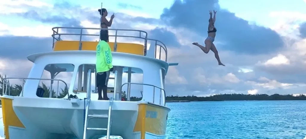 Woman jumping off a boat into the sea during a friends' reunion in the caribbean