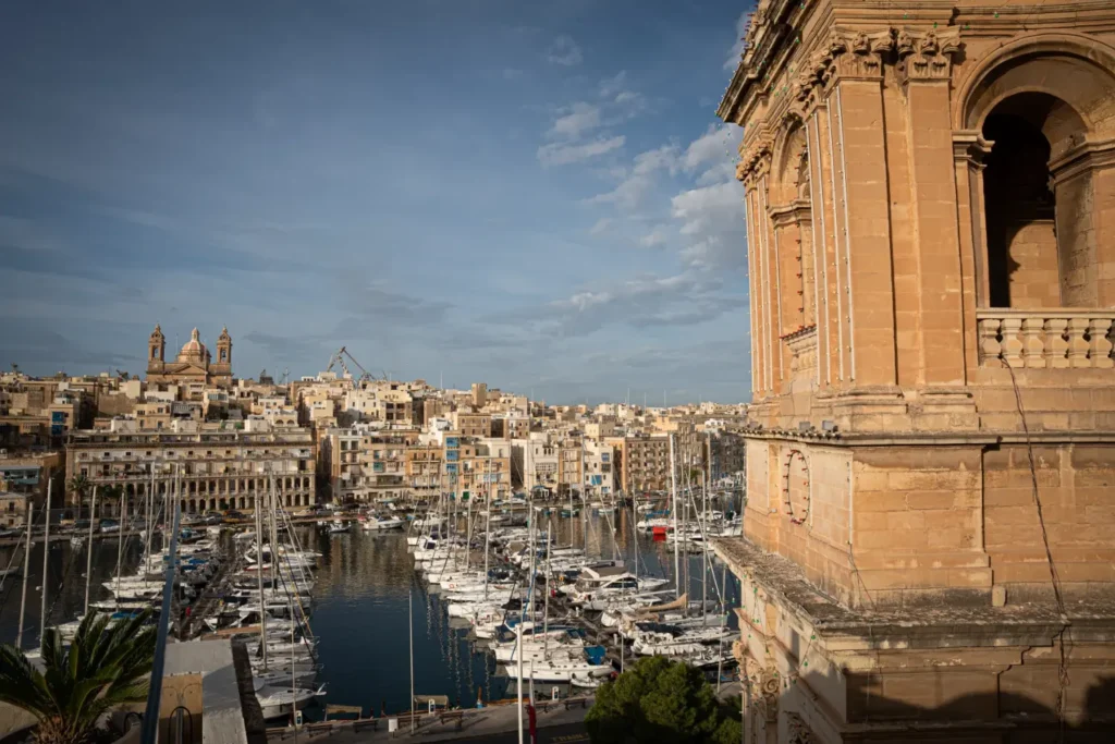 Yachts in Malta’s Grand Harbour beneath Birgu’s honey-colored buildings and church domes.