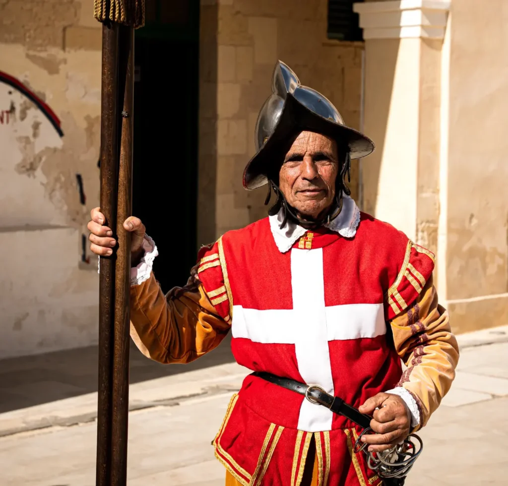 Reenactment soldier in a red uniform with white cross and helmet standing in the courtyard of Fort St. Elmo in Malta.