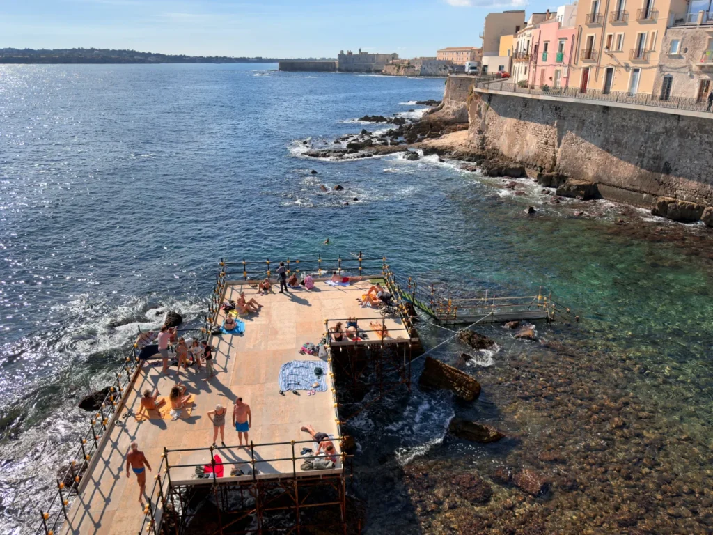Original photo by paul partridge of sunbathers and swimmers at the forte vigliena solarium sundeck in ortigia, sicily.
