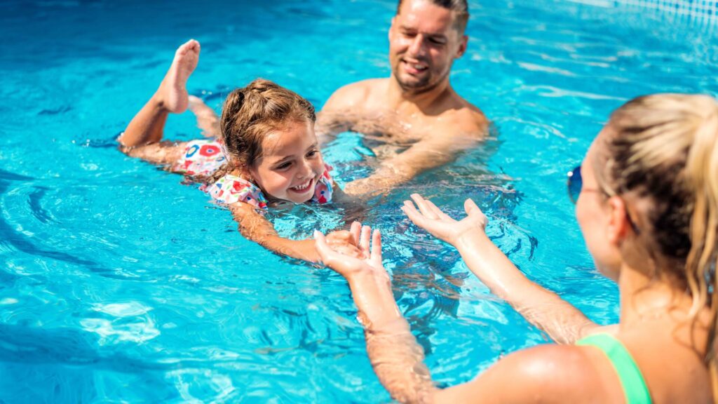 Parents teaching their daughter swimming pool 11zon
