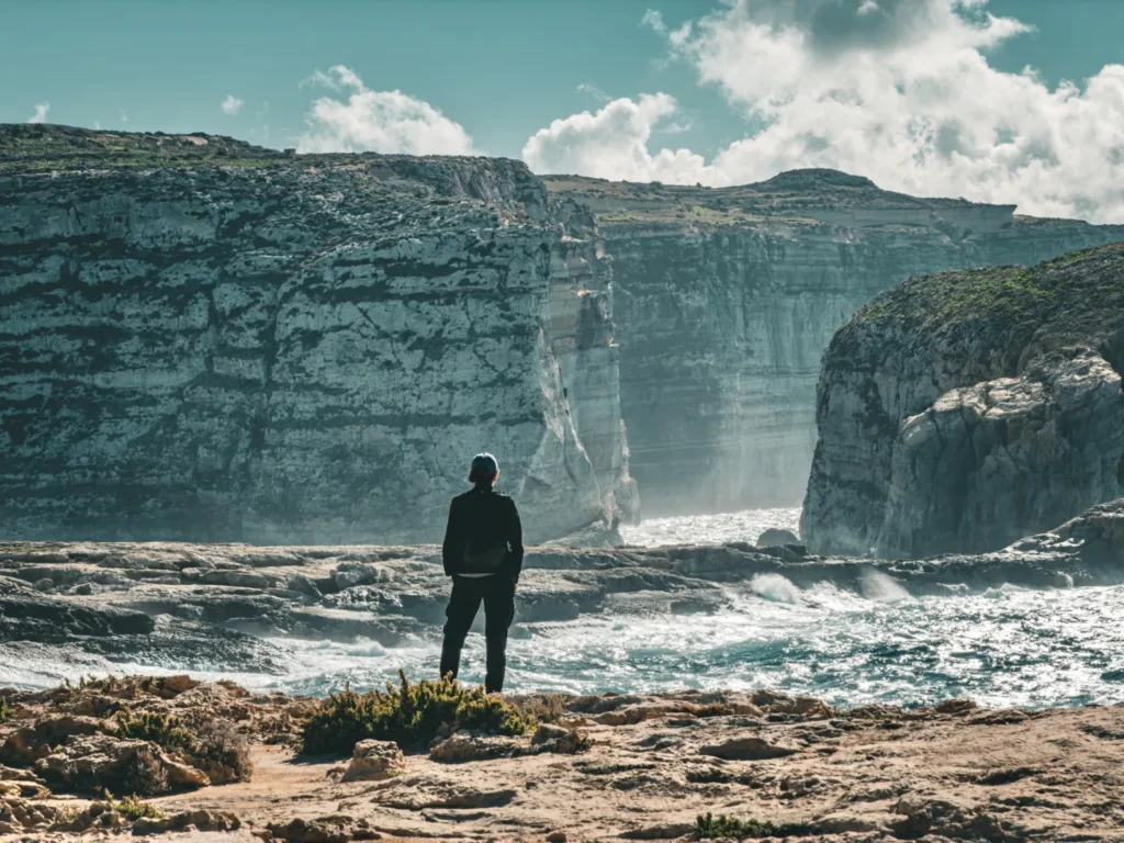 Original photo by paul partridge of a traveler admiring the rocky coastline of dwejra bay in gozo, malta.
