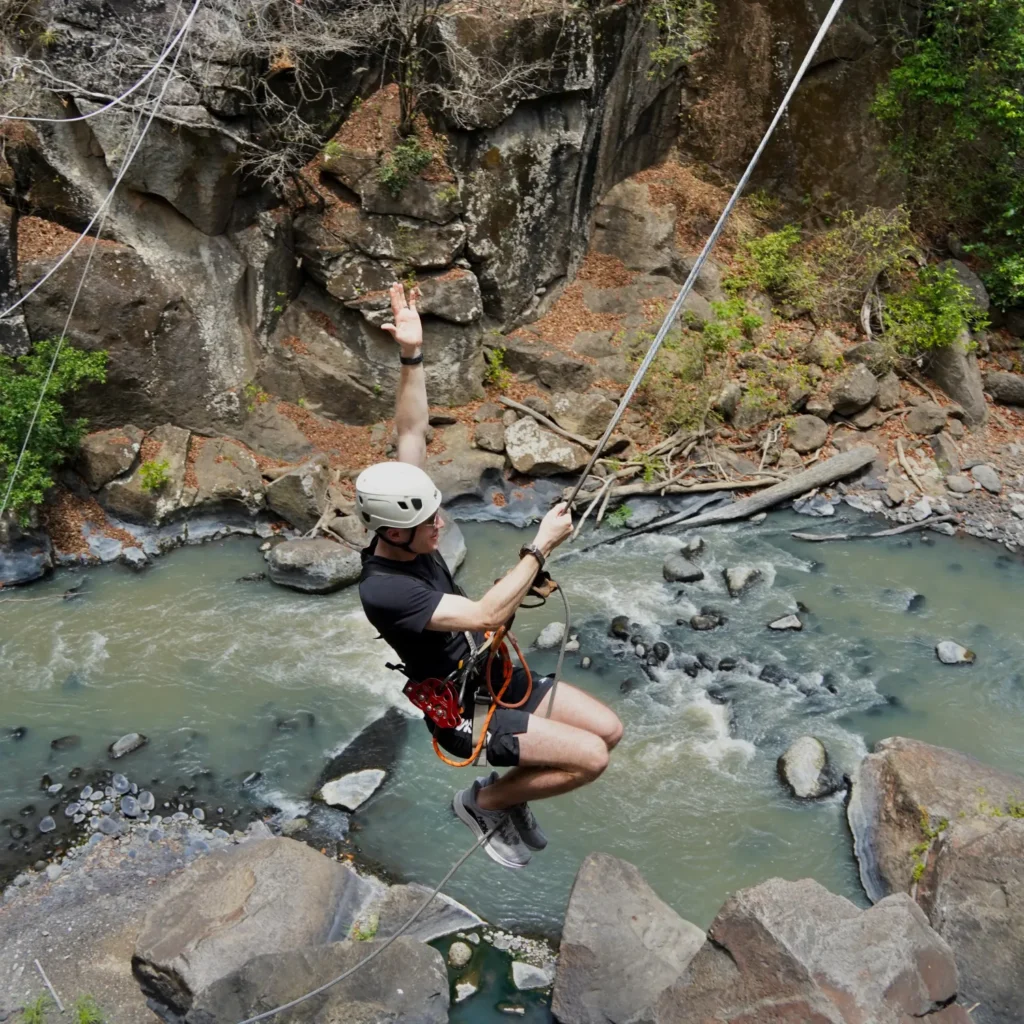 Original photo by paul partridge of a man ziplining above a rocky river during a celebration travel adventure in costa rica.