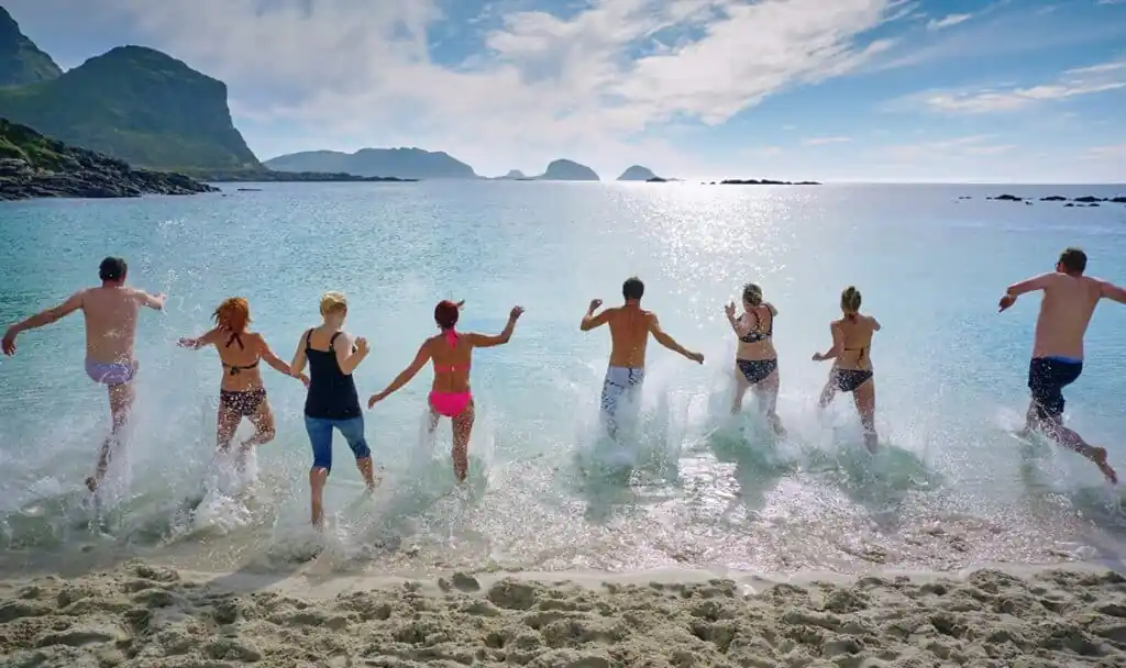 A group of people lined up running toward the water on the beach