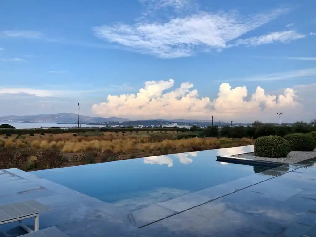Original photo by paul partridge of an infinity pool overlooking a scenic landscape, with distant mountains and the sea.