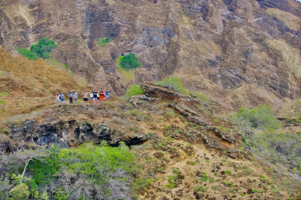 Group of friends on a friends' trip pause on a hiking trail to take photos of the pacific ocean.